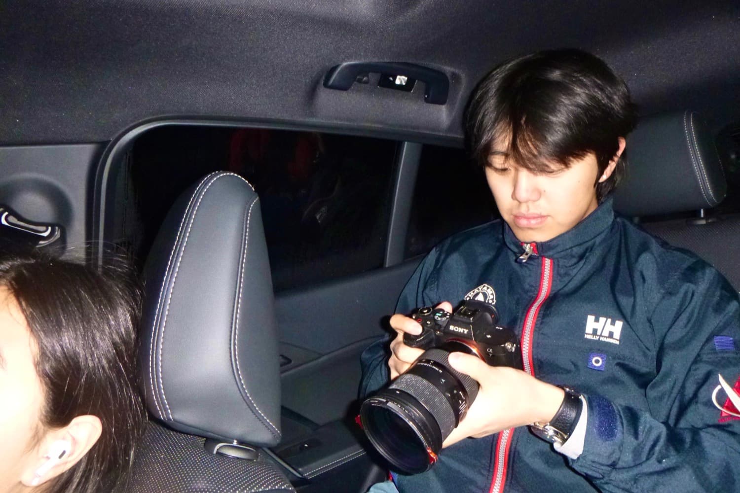 Daniel in the back seat of a car at night, reviewing a shot on the camera screen